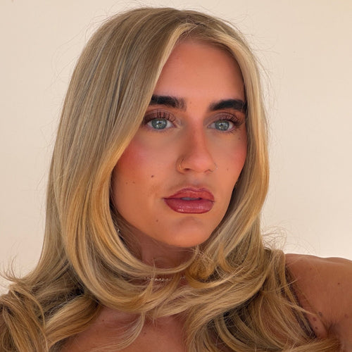 Close-up of a person with blonde hair and blue eyes against a plain background